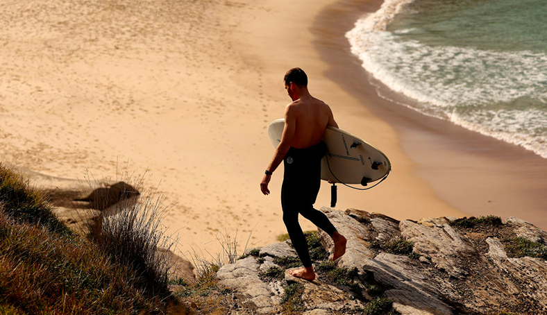 Un surfeur marche sur une plage de la côte Basque